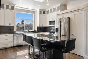 Kitchen featuring sink, dark wood-type flooring, stainless steel appliances, a center island, and a kitchen bar