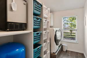 Laundry room with washing machine and dryer, dark wood-type flooring, and cabinets