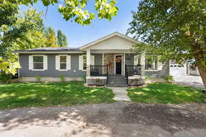 View of front of house with a front lawn, covered porch, and a garage