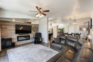 Living room with a textured ceiling, ceiling fan with notable chandelier, dark hardwood / wood-style flooring, and lofted ceiling