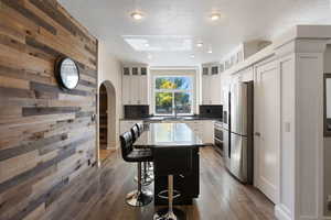 Kitchen with stainless steel appliances, dark hardwood / wood-style floors, white cabinetry, and a kitchen island