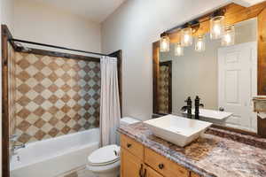 Full bathroom featuring shower / tub combo with curtain, tile patterned floors, vanity, and toilet