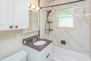 Full bathroom featuring tiled shower / bath combo, vanity, and toilet