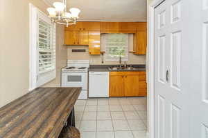 Kitchen featuring sink, an inviting chandelier, white appliances, decorative light fixtures, and light tile patterned floors