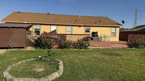 Rear view of house featuring a deck and a lawn