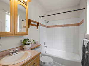 Full bathroom with tiled shower / bath, vanity, and toilet