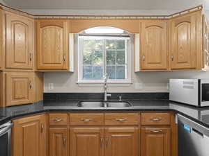 Kitchen featuring appliances with stainless steel finishes, sink, and dark stone counters