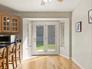 Doorway with a textured ceiling, light hardwood / wood-style floors, and ceiling fan