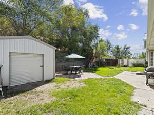 View of backyard, patio,  and shed.