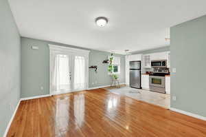 Kitchen featuring french doors, white cabinets, stainless steel appliances, and light tile flooring