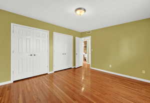 Unfurnished bedroom with multiple closets and light hardwood  floors