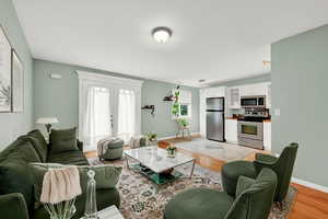 Living room with french doors and light hardwood flooring, Virtually Staged Distortions may be visible and are due to AI.