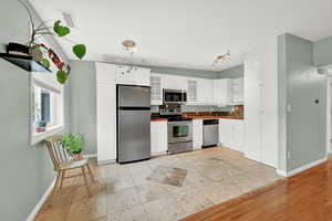 Kitchen with light tile floors, white cabinetry, stainless steel appliances, and tasteful backsplash