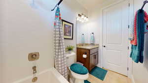 Full bathroom with shower / tub combo, vanity, toilet, and tile patterned floors