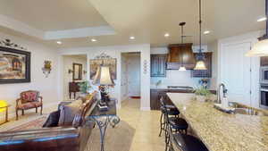 Kitchen featuring light stone counters, hanging light fixtures, sink, appliances with stainless steel finishes, and decorative backsplash