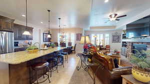 Living room with a fireplace, ceiling fan, light tile patterned floors, and sink