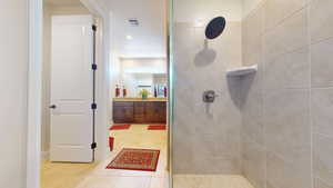 Bathroom featuring a tile shower, tile patterned flooring, and vanity