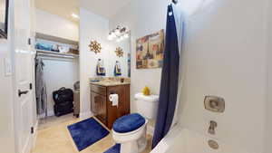 Full bathroom with shower / tub combo with curtain, tile patterned floors, vanity, and toilet