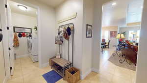 Hall with washer and clothes dryer and light tile patterned floors