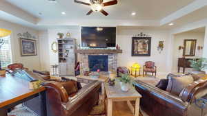 Living room featuring a tray ceiling, ceiling fan, and carpet floors