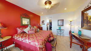 Bedroom with ceiling fan, light colored carpet, and ensuite bath