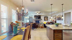 Kitchen with light colored carpet, decorative light fixtures, a stone fireplace, light stone countertops, and stainless steel dishwasher