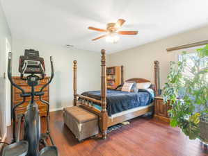 Primary bedroom with ceiling fan and dark wood-style floors