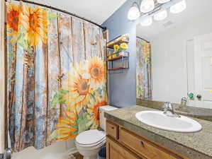 Full bathroom featuring shower / bath combo, vanity, and toilet