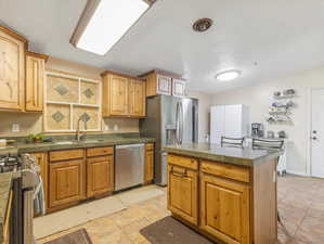 Kitchen featuring appliances with stainless steel finishes, island, tile floors