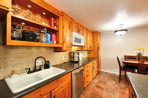 Kitchen with dishwasher, a textured ceiling, tasteful backsplash, and sink