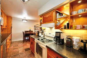 Kitchen with a textured ceiling, tasteful backsplash, and white appliances