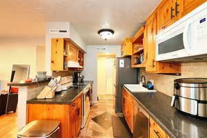 Kitchen featuring dishwasher, a textured ceiling, electric range, sink, and backsplash