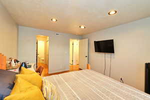 Bedroom featuring ensuite bath, light hardwood / wood-style floors, and a textured ceiling