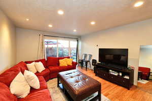 Living room with light hardwood / wood-style flooring and a textured ceiling