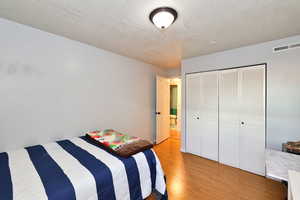 Bedroom featuring a textured ceiling, light hardwood / wood-style floors, and a closet