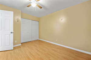 Unfurnished bedroom with a closet, light wood-type flooring, and ceiling fan