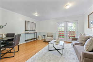 Living room featuring ornamental molding, french doors, and light hardwood / wood-style flooring