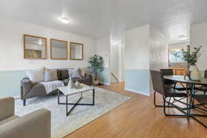 Living room with ornamental molding, a textured ceiling, sink, and light wood-type flooring