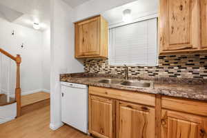 Kitchen featuring white dishwasher, light hardwood / wood-style flooring, backsplash, and sink