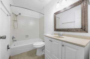 Full bathroom with tiled shower / bath, vanity, tile patterned flooring, and toilet