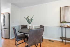 Dining space featuring ornamental molding and light wood-type flooring