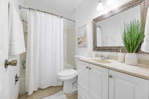 Full bathroom featuring vanity, shower / bathtub combination with curtain, toilet, and tile patterned floors