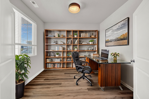 Office space featuring dark wood-type LVP flooring. Virtually staged