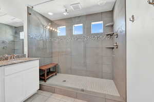 Bathroom featuring tile patterned flooring, vanity, and tiled shower