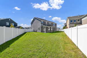 Rear view of property with central AC unit and a lawn