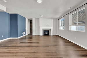 Unfurnished living room featuring a textured ceiling, dark hardwood / wood-style  LVP floors, and a fireplace