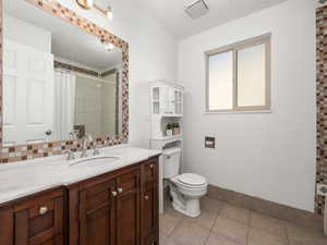 Bathroom with toilet, tile patterned floors, a shower with shower curtain, and vanity