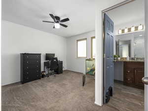 Carpeted office space with ceiling fan and sink