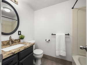 Full bathroom with toilet, vanity, tile patterned floors, bathing tub / shower combination, and a textured ceiling