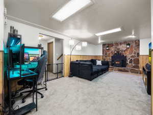 Office area with a textured ceiling, wooden walls, a wood stove, and carpet flooring